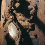 Rust-encrusted ornate oval mirror on wood