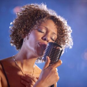 Woman singing into vintage microphone on stage