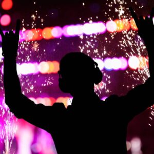 DJ silhouette with headphones amid stage sparks