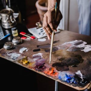 Hand holding brush mixing paints on palette
