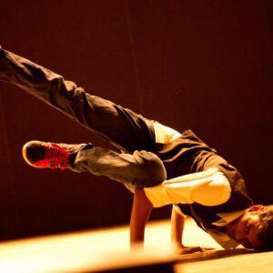 Breakdancer performing one-handed freeze in spotlight